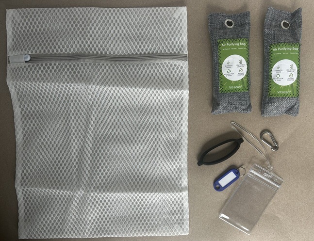 Active Family Kit flat lay showing mesh laundry bag, silicone water bottle sling, carabiner clip, bamboo charcoal odor bags, and backpack ID tag